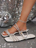 Close view of white rhinestone flat sandal straps and smooth footbed