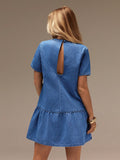 Blue denim dress with cut-out back on a model against a brown background