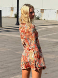 Rear three-quarter view of multicolor botanical mini dress with flared cuffs in an outdoor setting