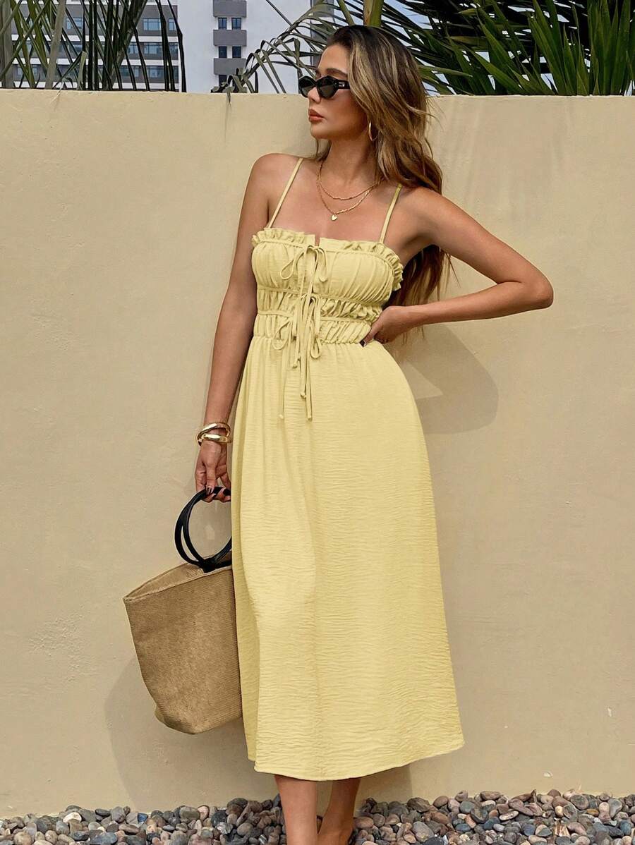 Pale yellow tie-front midi sundress with ruffle trim on pebble patio