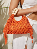 Orange crochet beach bag held at waist with hollow weave tassels and cream bead handle