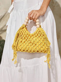 Yellow crochet beach bag held by model with hollow knit tassels and bead handle