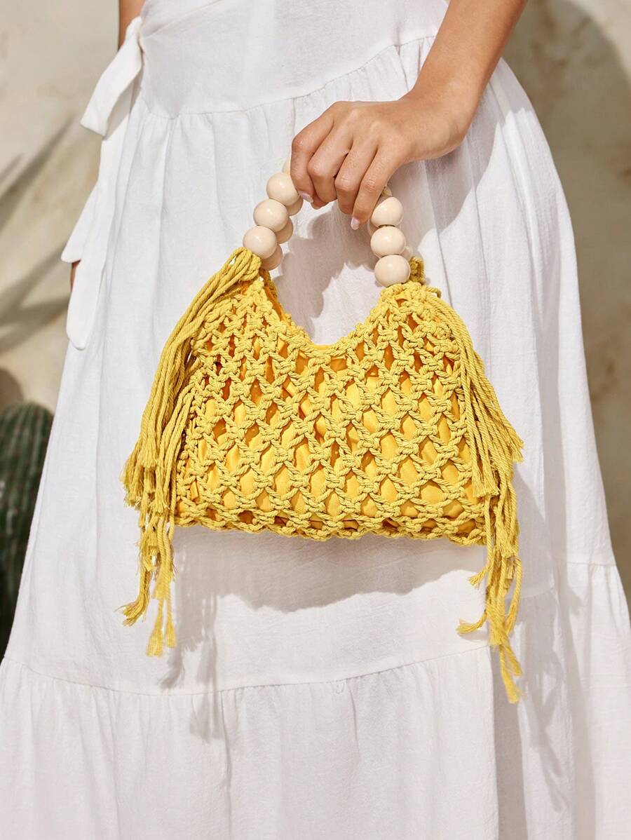 Yellow crochet beach bag held by model with hollow knit tassels and bead handle