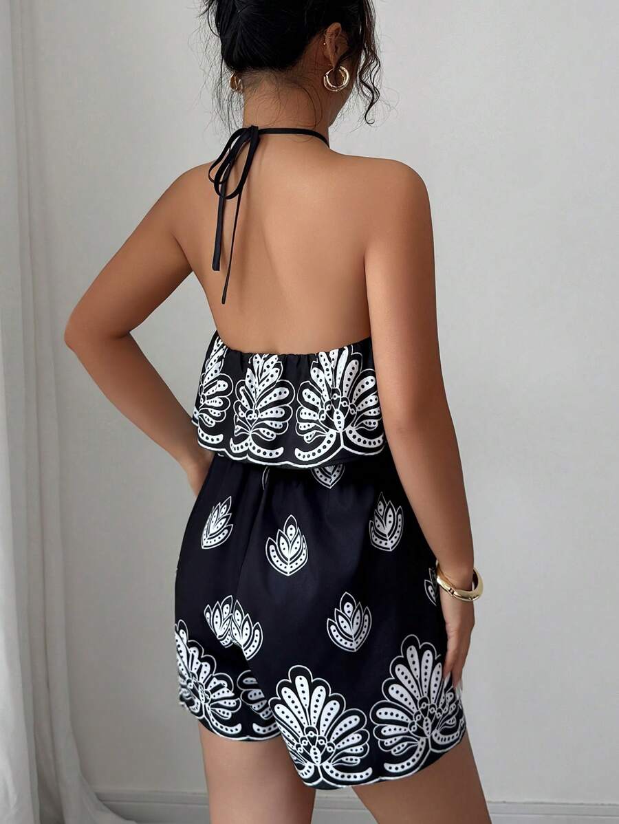 Mirror front view of black printed halter romper with layered ruffle bodice and gathered waist