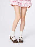 Full-body front view of brown Mary Jane flats styled with a pink ruffled skirt