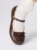 Close-up front view of brown round-toe flat with large bow and gold-tone clasp