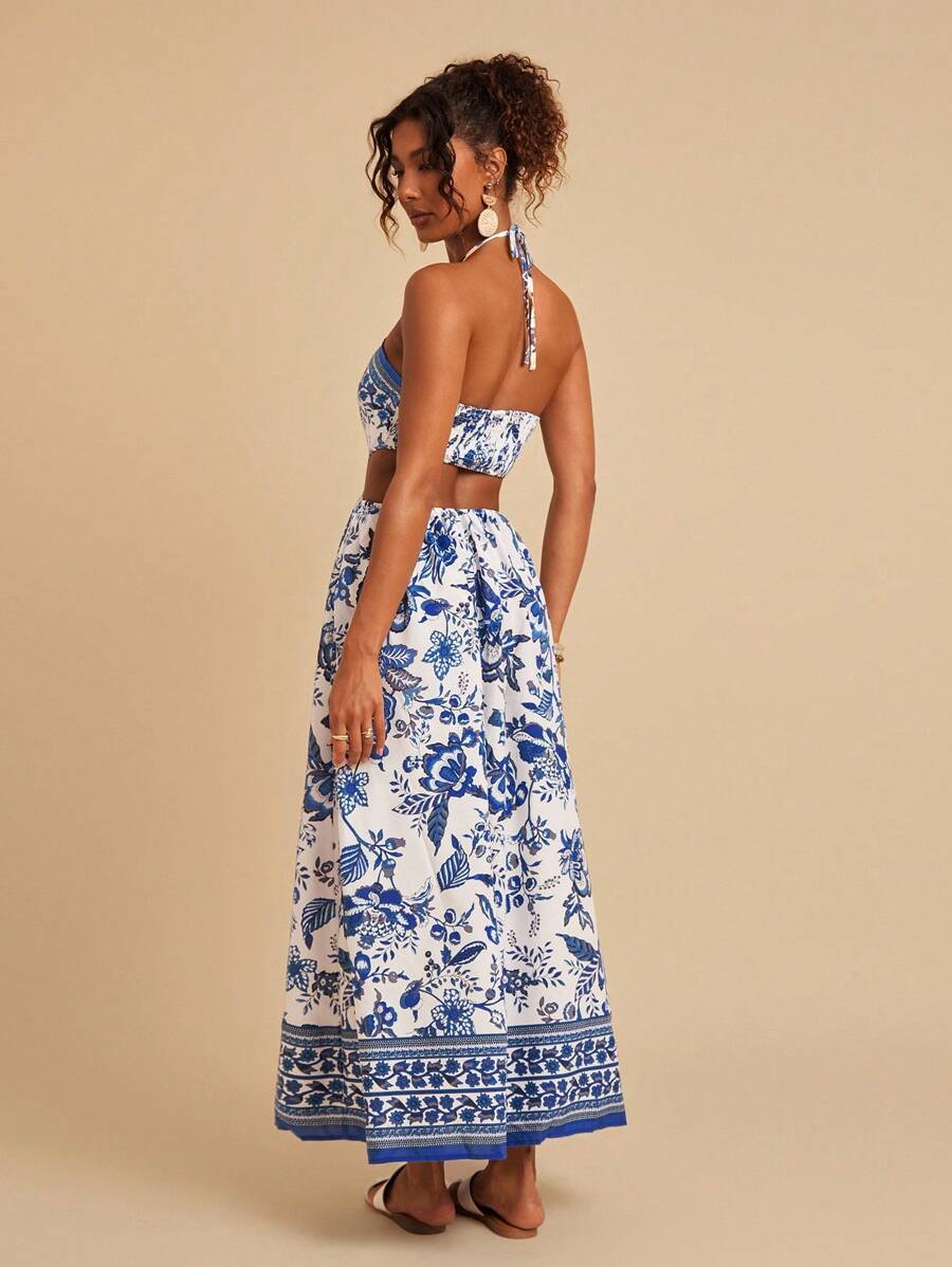 Embrace effortless summer elegance with this stunning floral print halter dress. Featuring a captivating blue and white botanical design, this maxi dress showcases a chic tie-back halter neckline and high-waisted silhouette for a flattering fit. The thigh-high slit and shirred details add movement and dimension, while the sleeveless cami cut keeps you cool and comfortable. Crafted from a breathable woven polyester-elastane blend, this versatile piece transitions seamlessly from casual outings to special occ