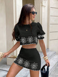 Black crop top and mini skirt set with white daisy embroidery, puff sleeves, and scalloped hems