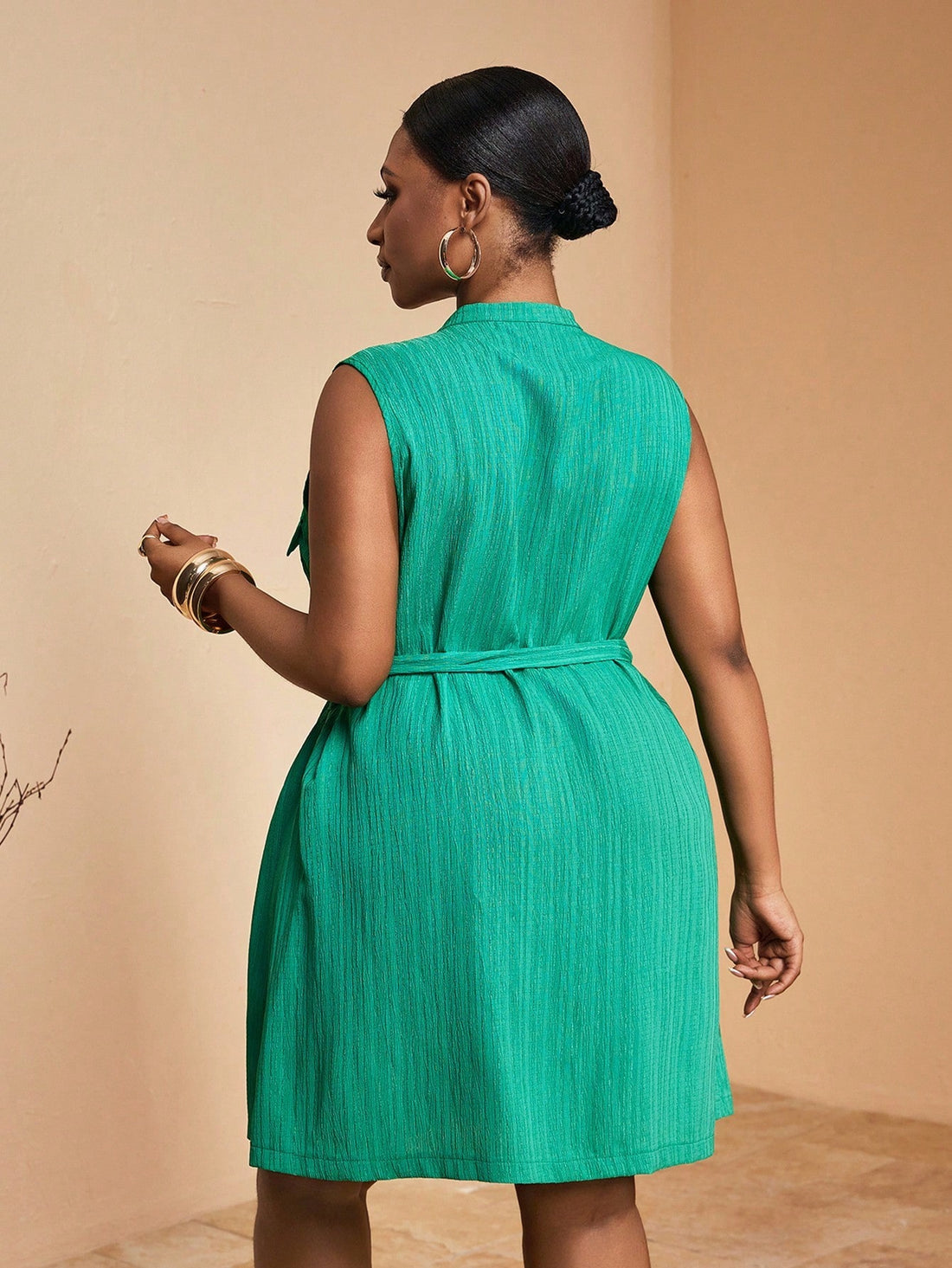 Turn heads with this playful yet elegant plus size mini shirt dress in a rich dark green shade. Its sleeveless design and flattering mandarin collar bring a fresh, stylish edge, while the coordinating belt cinches your waist for a perfect fit. Effortlessly chic, this dress is your go-to for making a confident statement wherever you go.