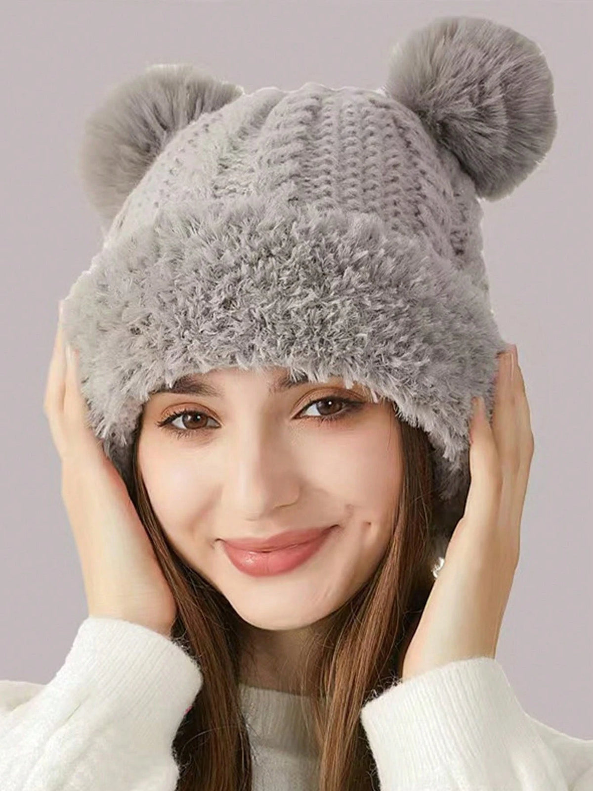 Close portrait of gray plush bear-ear hat with rounded poms and face-framing trim