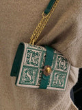 Green trim structured box bag showing flap closure and ornate front panels