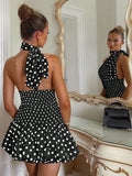 Woman wearing a black polka dot dress in front of a mirror.