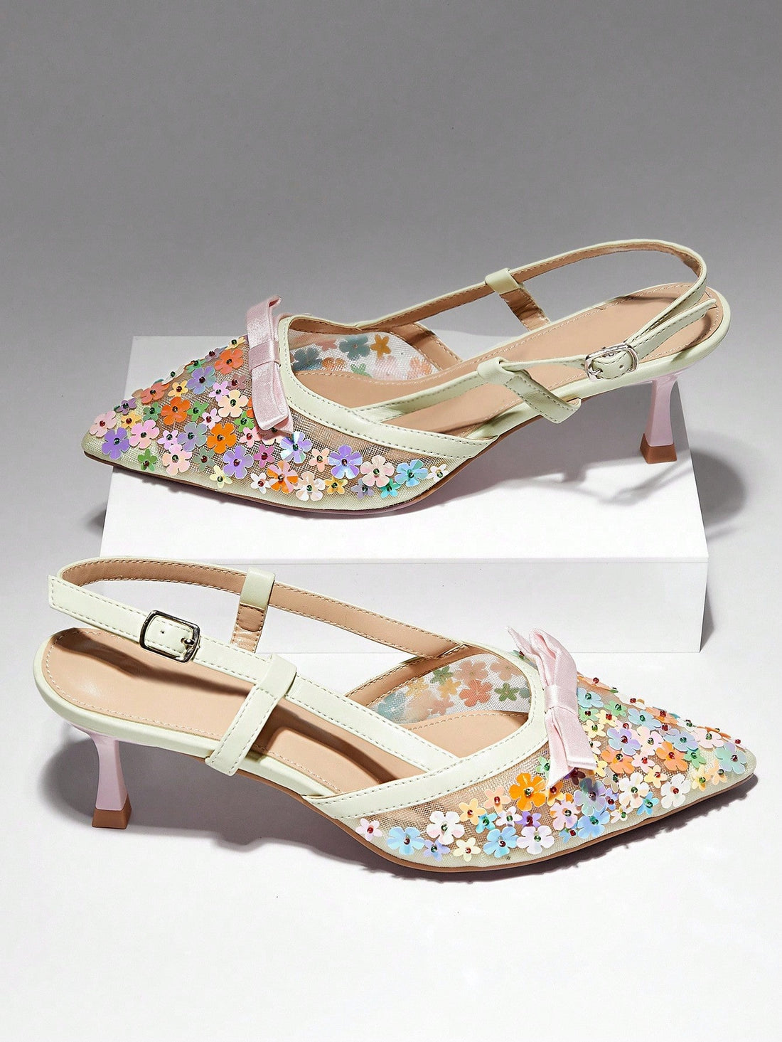 Sophisticated mesh pumps featuring delicate floral embellishments and a secure slingback design. The breathable mesh construction offers all-day comfort while maintaining an elevated aesthetic, perfect for formal occasions or refined everyday wear. The slingback strap provides stability and a polished silhouette. Ideal for those seeking footwear that balances elegance with wearability.