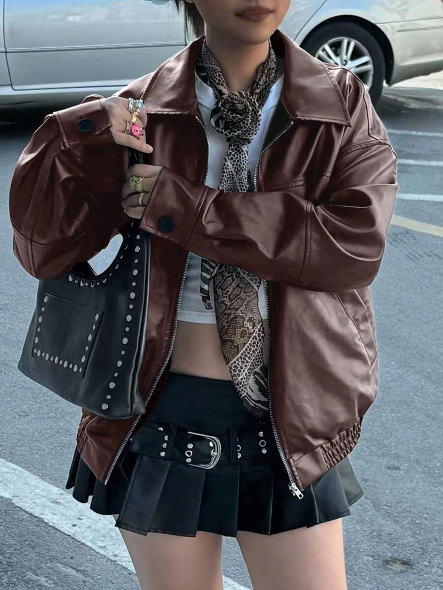 Front view of coffee brown faux leather bomber jacket styled with pleated skirt