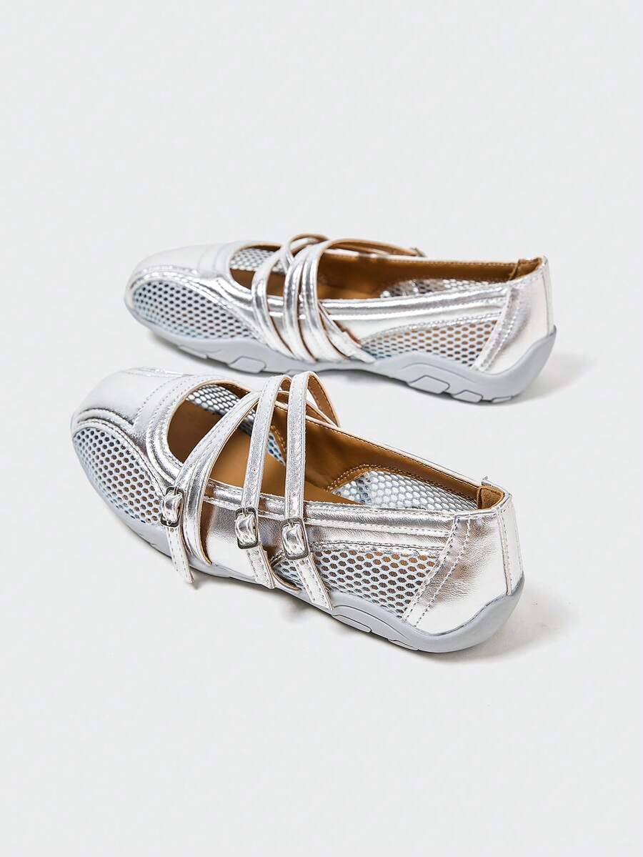Front three-quarter view of silver three-strap Mary Jane flats with mesh panels and segmented sole