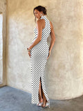 Back view of white polka dot halter maxi dress with rear slit and fitted shape