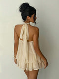 Back view of beige open back halter mini dress with long tie straps