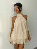 Full front view of beige backless halter mini dress styled for summer travel