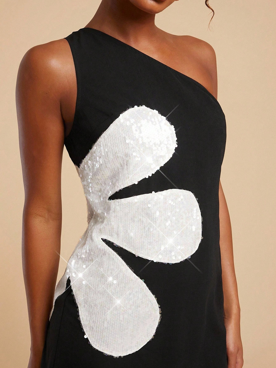 Turn heads in this playful one-shoulder mini dress shimmering with black and white floral sequins. Its sparkling design adds a fun twist to elegance, perfect for dancing the night away or making a bold statement at any event. Lightweight and eye-catching, this dress combines style and flair effortlessly.