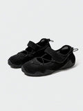 Front-quarter view of black mesh water shoe with hook-and-loop strap and patterned sole