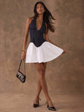 Full front view of colorblock halter mini dress styled with heels and shoulder bag
