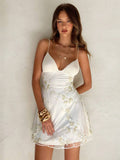 Detail view of ivory white floral embroidered spaghetti strap mini dress with close flower applique