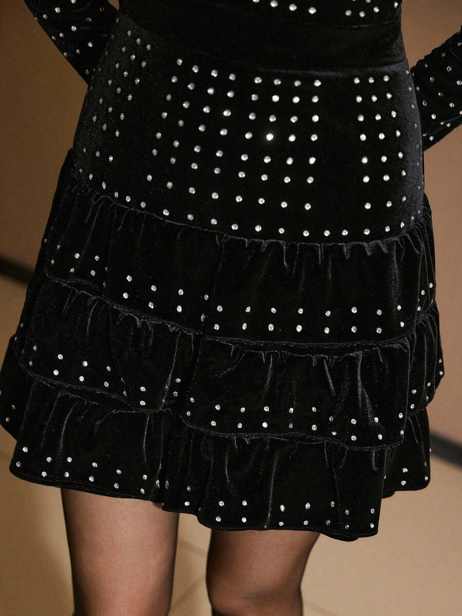 Front three-quarter view of black rhinestone velvet mini dress with long sleeves and tiered ruffles