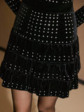 Close-up of black velvet mini dress showing rhinestone accents and gathered ruffle tiers