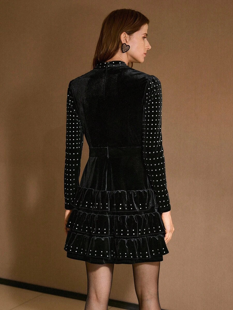 Back view of black long-sleeve velvet mini dress with fitted waist and tiered skirt