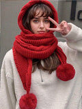 Red knitted hood scarf with two large pom-pom ends modeled front view