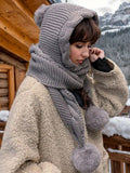Gray chunky-knit hood scarf with long wrap and pom-pom ends, side view