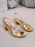 Gold high-heeled shoes on a light gray surface