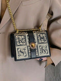 Black structured box bag showing ornate square front panels and flap closure
