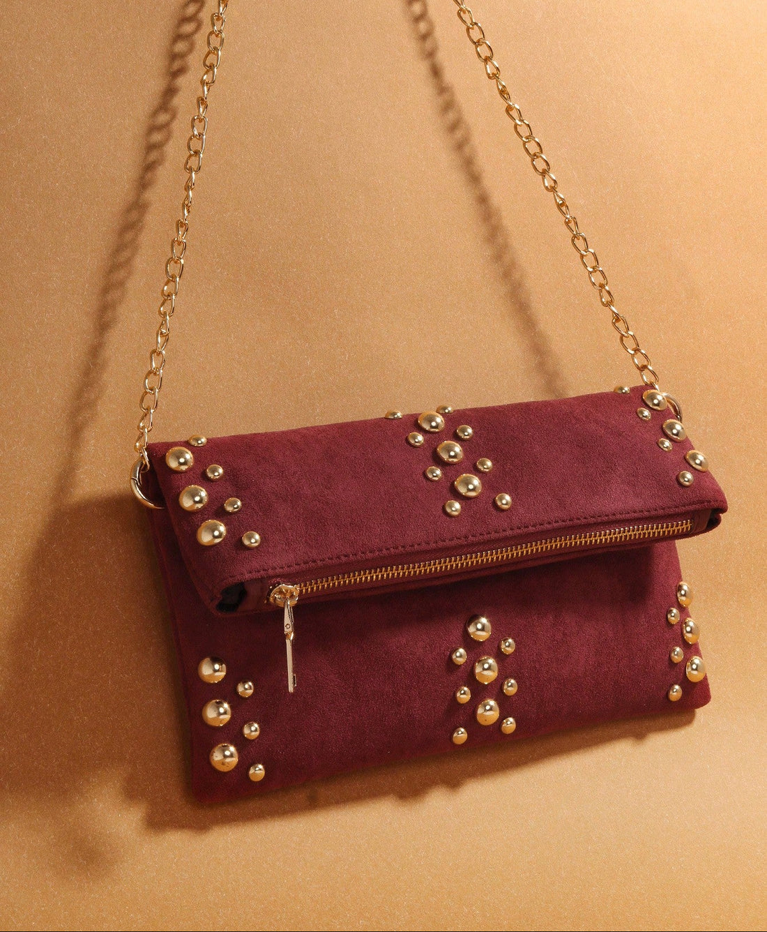 Make a statement with this stunning burgundy suede bag that's equal parts edgy and elegant. Adorned with eye-catching gold rivet details and a sleek chain strap, it's the perfect accessory for anyone who refuses to blend in. The spacious interior keeps your daily essentials organized without sacrificing style, while the rich burgundy hue pairs effortlessly with any outfit. Whether you're heading to brunch or a night out, this bold beauty delivers attitude and sophistication in one fabulous package.