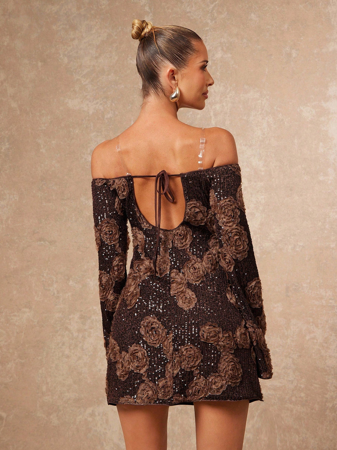 Turn heads at every holiday bash with this glamorous brown off-shoulder mini dress. Covered in shimmering sequins, it catches the light beautifully, making you the sparkle of any special occasion. The playful off-shoulder design adds a flirty touch while the mini length keeps things fun and festive. Perfect for dancing the night away in style!