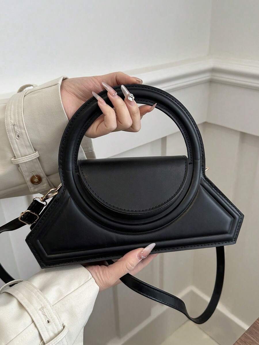 Lifestyle front view of black structured crossbody bag with round handle and half moon flap