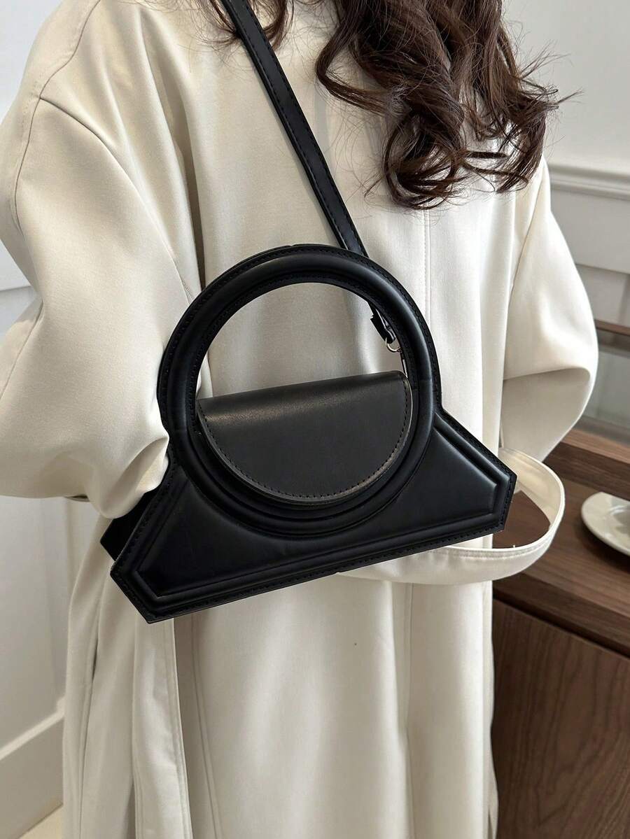 Lifestyle front view of black structured crossbody bag with round handle and half moon flap