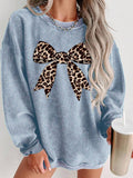 Front worn view of baby blue oversized sweatshirt with leopard-print bow graphic