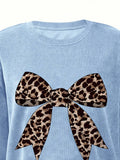 Close-up of leopard-print bow graphic on baby blue crew-neck sweatshirt