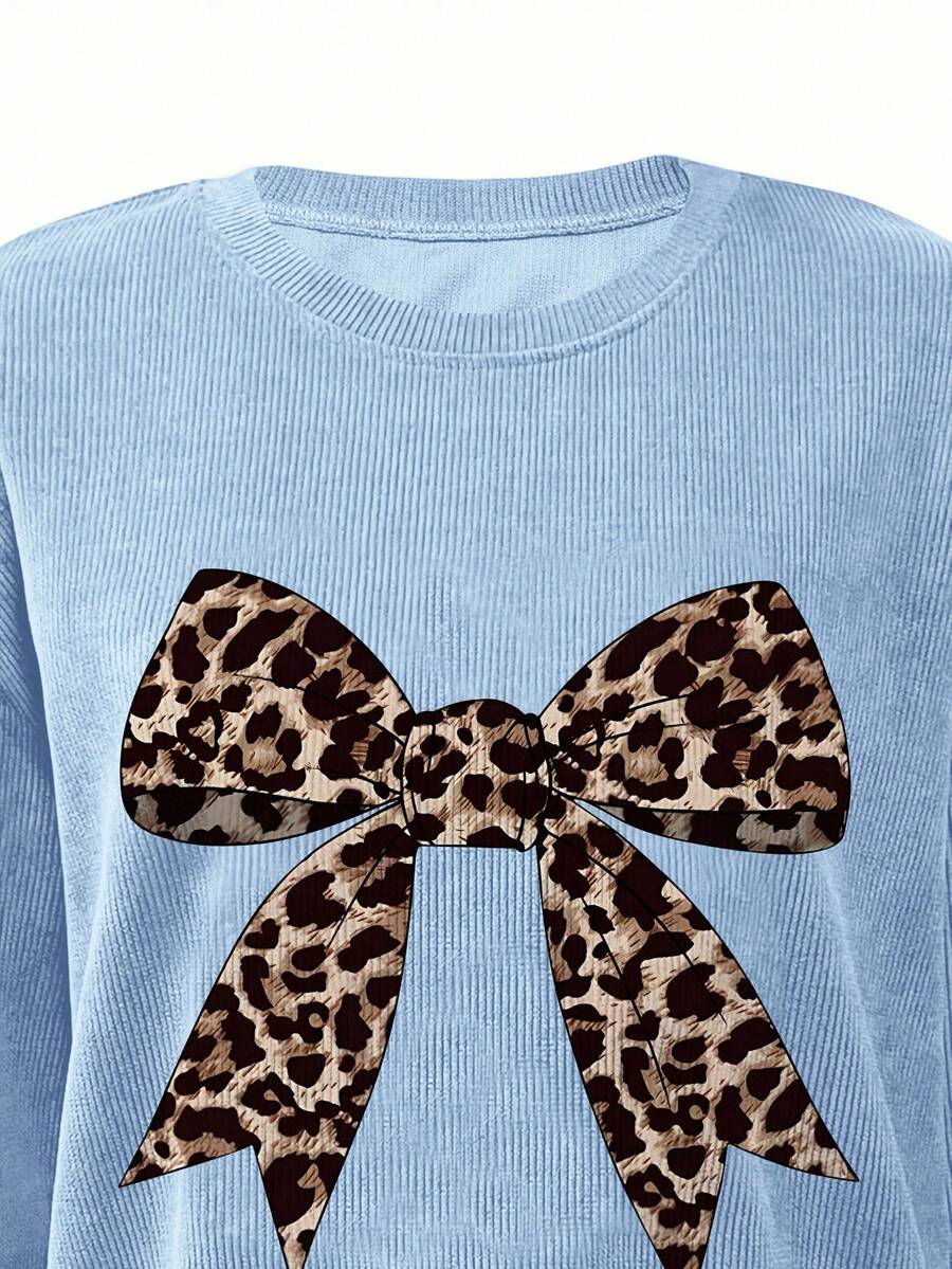 Close-up of leopard-print bow graphic on baby blue crew-neck sweatshirt
