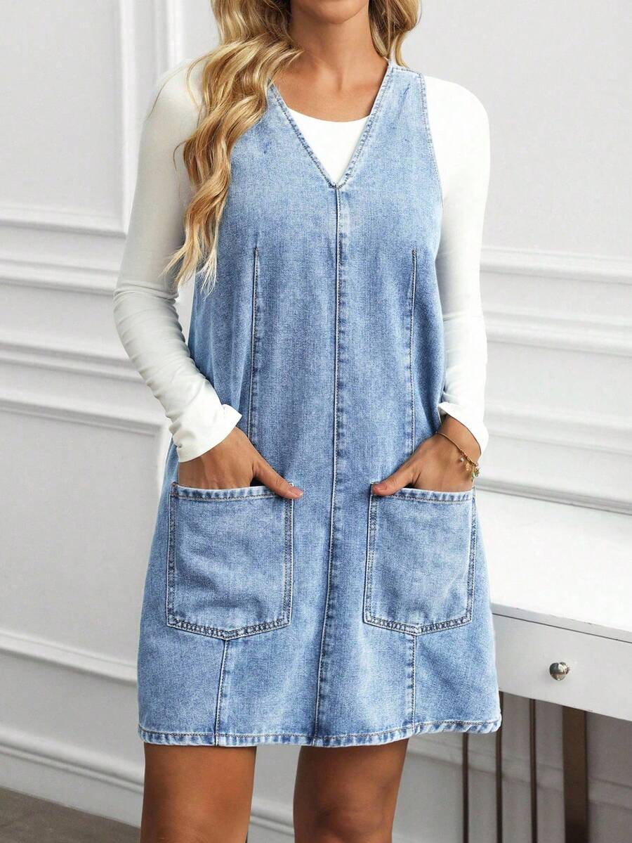Full front view of light-wash blue denim pinafore mini dress with roomy front pockets