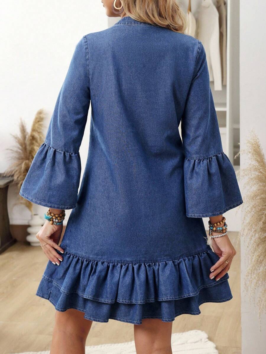 Rear view of blue A-line denim mini dress with bell sleeves and tiered hem