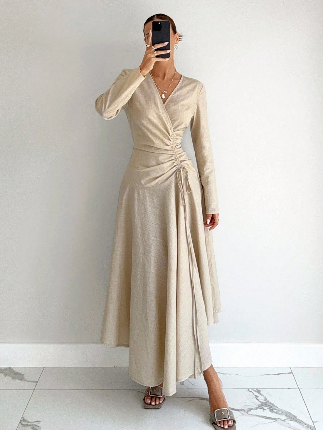 Wrap yourself in effortless sophistication with this stunning beige cotton-linen blend dress. The flattering wrap silhouette hugs your curves just right, while delicate pleating at the waist adds dimension and visual interest. An asymmetrical hem brings a modern twist to a timeless style, making it perfect for everything from brunch dates to evening outings. Breathable and comfortable, this versatile piece transitions seamlessly from season to season. Whether you're dressing up or keeping it casual, this dr