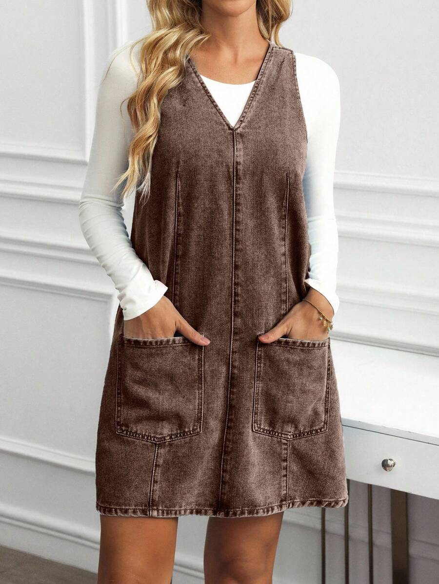 Full front view of coffee brown denim pinafore mini dress with two large patch pockets