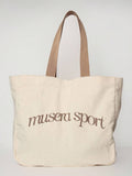 Close view of cream logo tote bag showing thick canvas and strap stitching