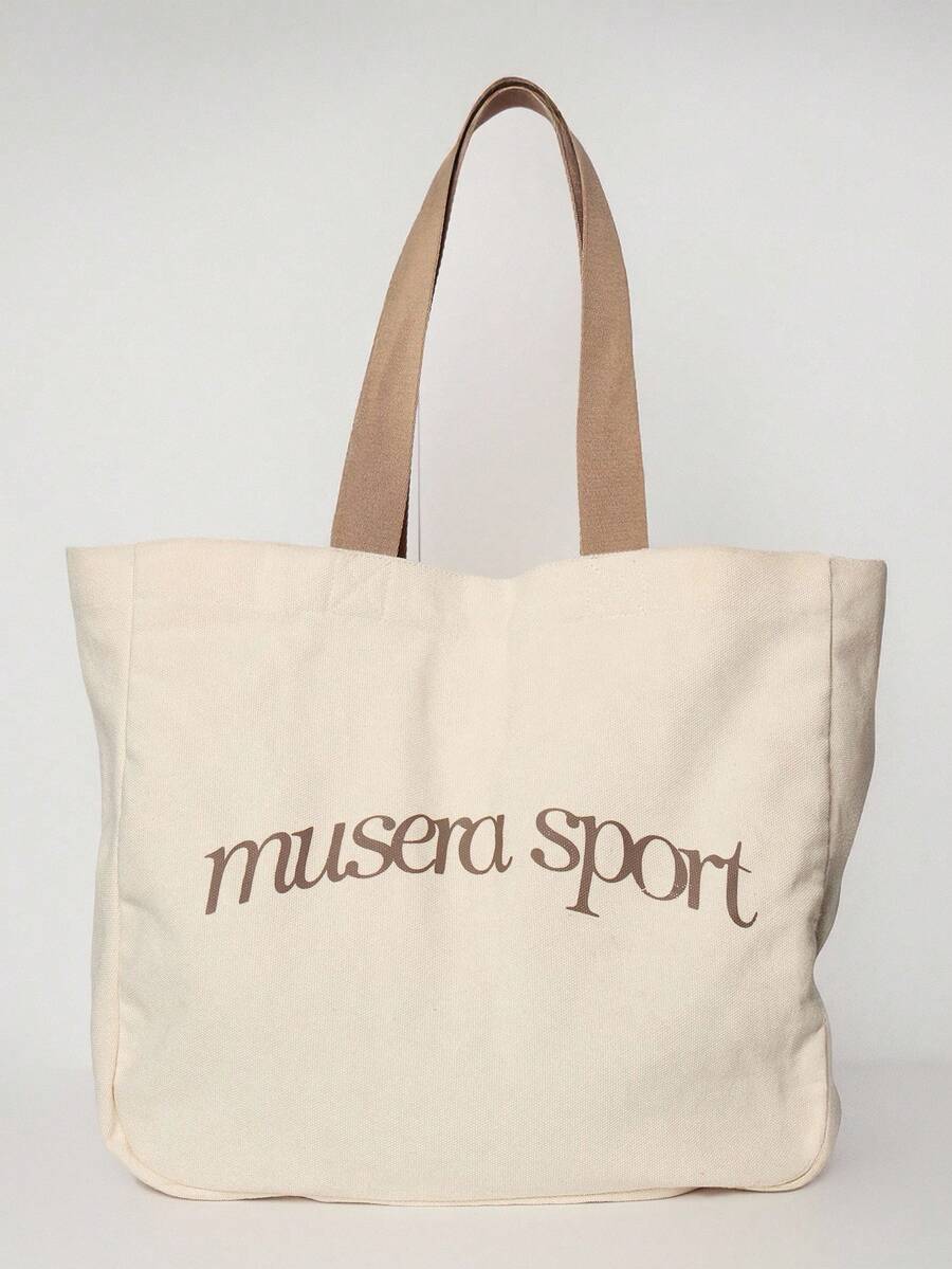 Close view of cream logo tote bag showing thick canvas and strap stitching
