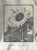 Close-up of dark charcoal sunflower and Grow in Grace print on gray sweatshirt front