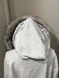 Close view of light grey hooded jacket with soft faux-fur hood trim