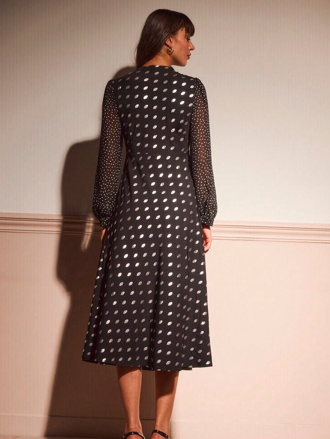 Elevate your autumn wardrobe with this stunning black midi dress that's equal parts sophisticated and fun. The vintage-inspired V-neckline and long sleeves offer timeless elegance, while shimmering metallic polka dots add a playful sparkle that catches the light beautifully. Perfect for dinner dates, cocktail parties, or any occasion calling for effortless chic style. The midi length provides a flattering silhouette that works for any body type, making this dress a versatile go-to piece for the cooler month