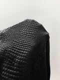 Macro view of black embossed crocodile texture on dress fabric